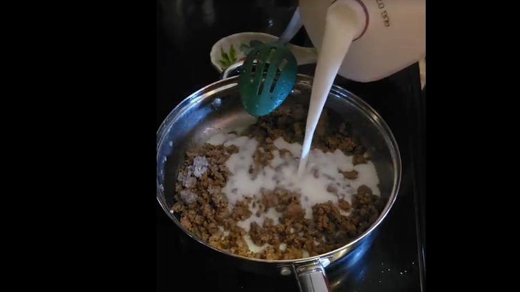 Adding milk to sausage gravy.